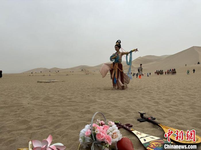 圖為2023年4月底，敦煌大漠“逐舞者”奧楠在鳴沙山月牙泉景區視頻直播敦煌舞。　馮志軍 攝