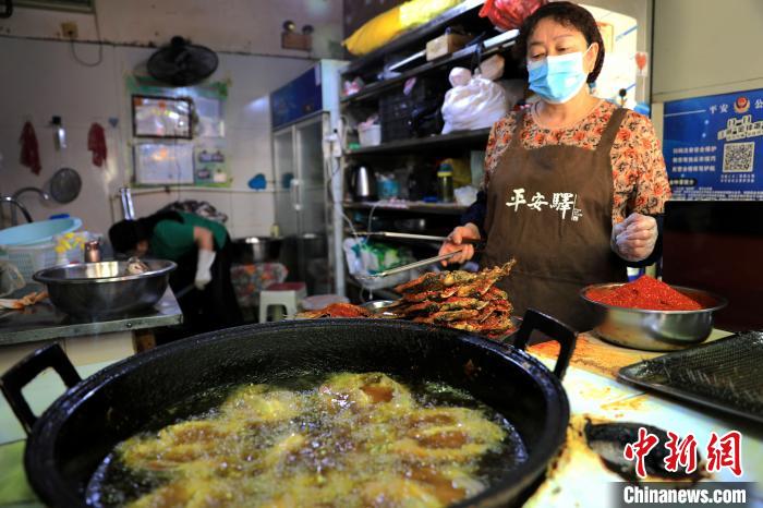 圖為平安驛·河湟民俗文化體驗地內的商戶炸干板魚?！⊙Φ?攝